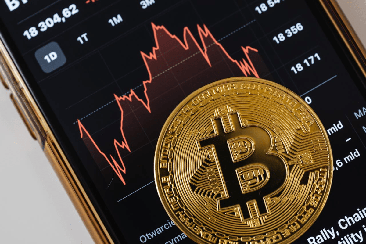 ETF Bitcoin - Goldene Bitcoin-Münze vor Kursdiagramm auf Smartphone